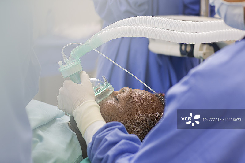 医生戴手术手套的特写，在手术室病人的氧气面罩图片素材