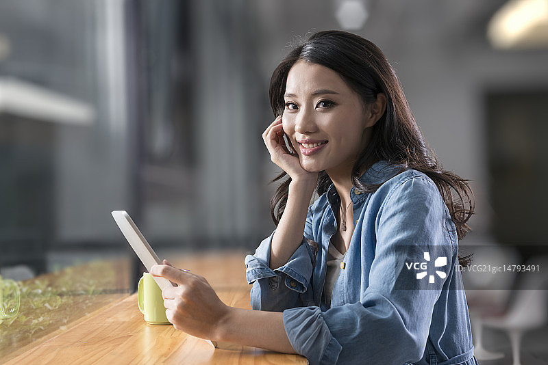 Creative businesswoman using digital tablet in break room图片素材