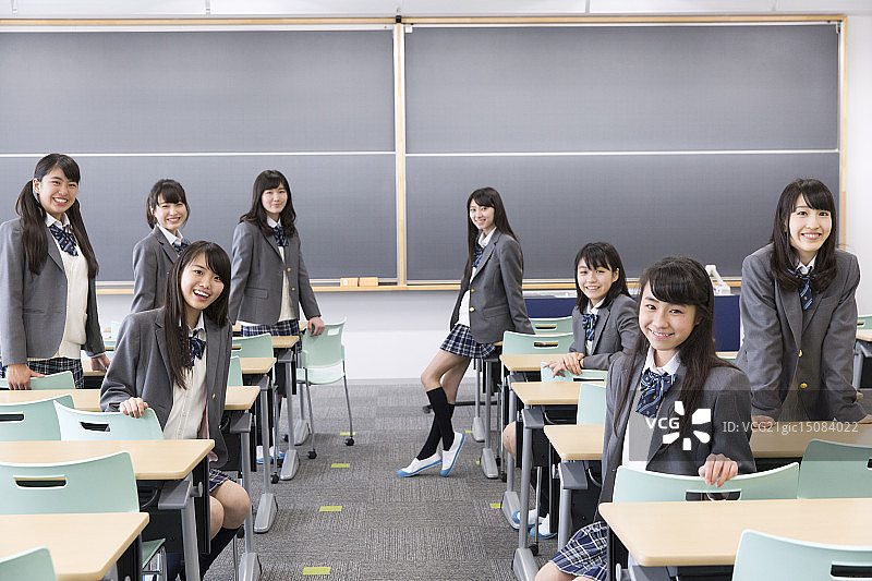欢快的高中女生坐在课桌前的肖像图片素材