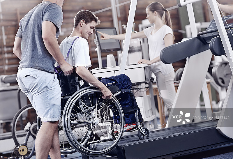 理疗师在跑步机上指导轮椅上的人图片素材