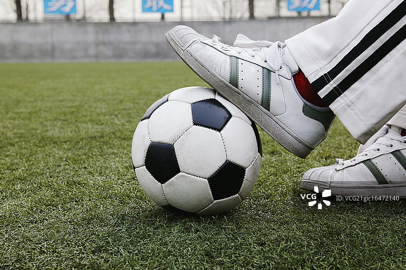 足球运动员踩在球上休息图片素材
