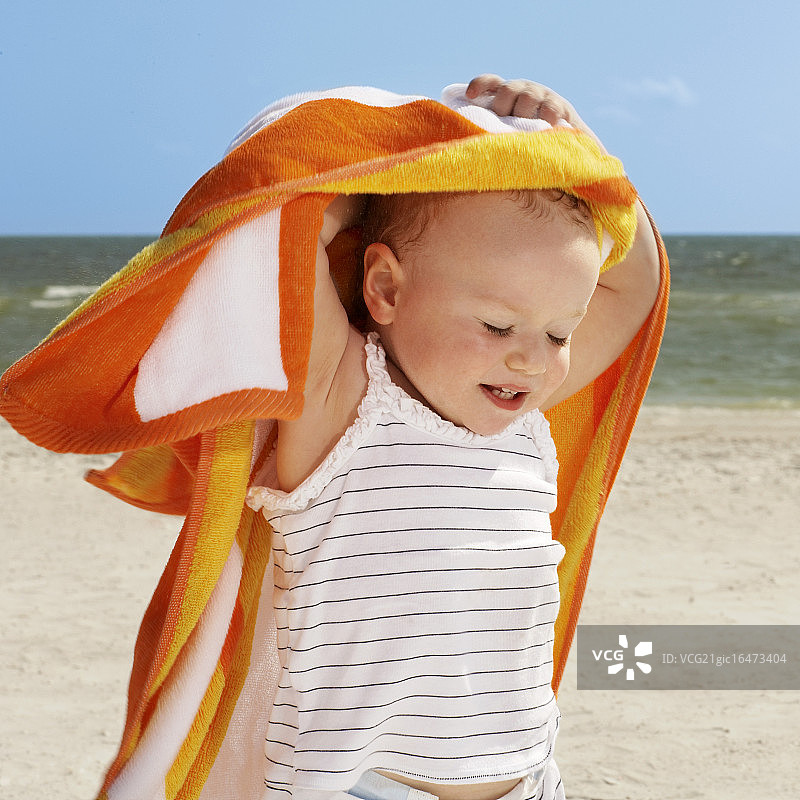 可爱的小女孩拿着毛巾在海滩上图片素材