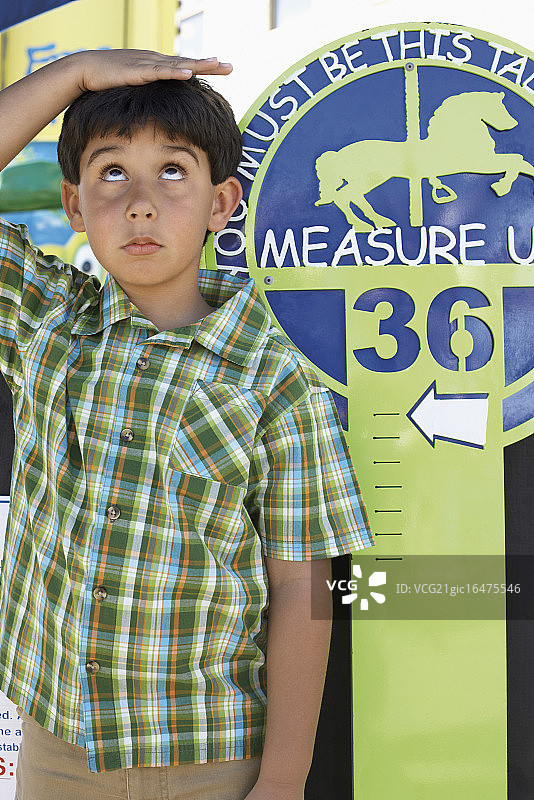 一个男孩在为游乐园的游乐设施测量身高图片素材