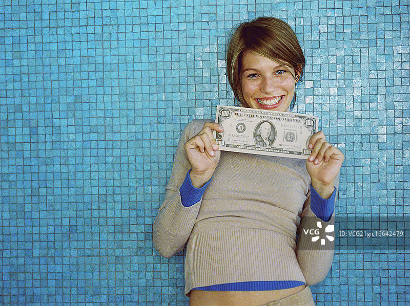 年轻女子手持超大面额的100美元钞票图片素材
