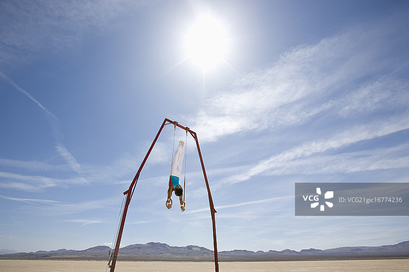 体操运动员在沙漠中表演固定环图片素材
