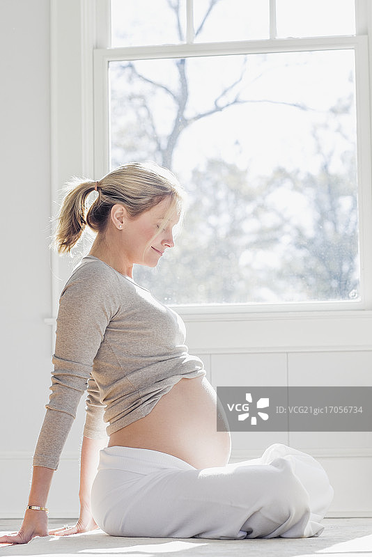 一个24周的孕妇看着她的肚子图片素材