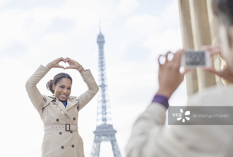 法国巴黎，一名男子在埃菲尔铁塔前为女友拍照图片素材