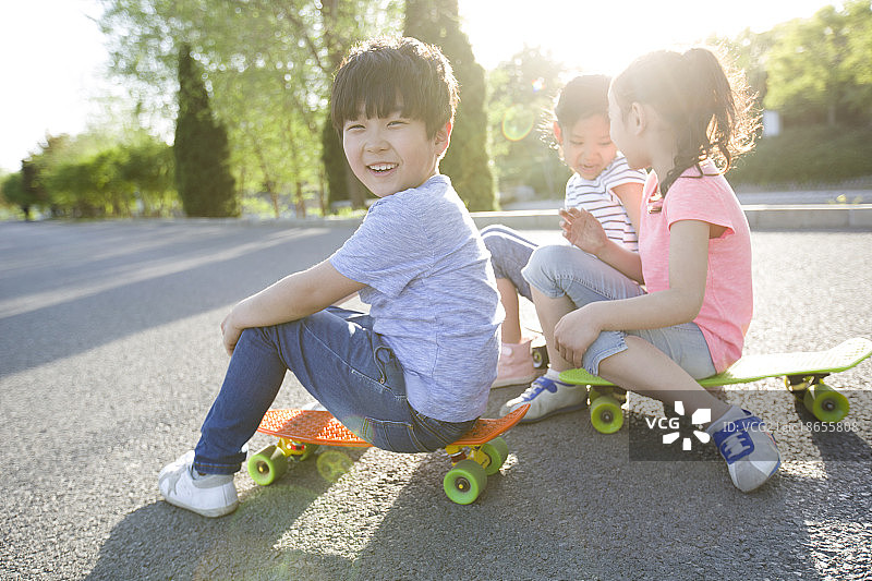 快乐的儿童坐在滑板上图片素材