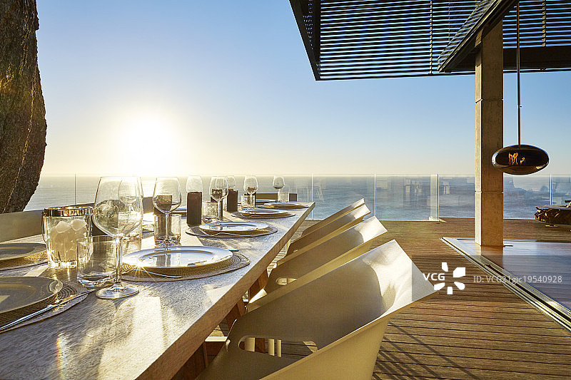 阳光照耀在豪华露台餐桌后的海洋与场所设置图片素材
