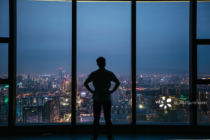 办公室里一个年轻人俯瞰城市的背影图片素材