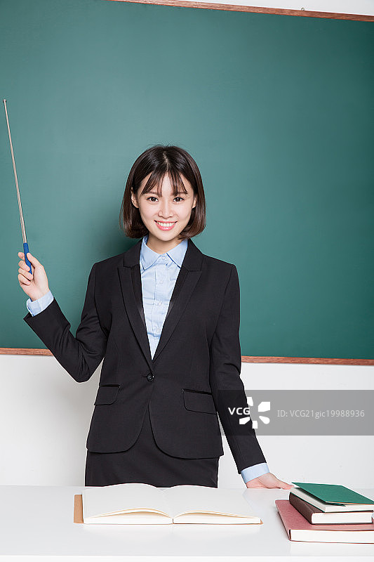 手持教棒的女教师,在黑板前图片素材