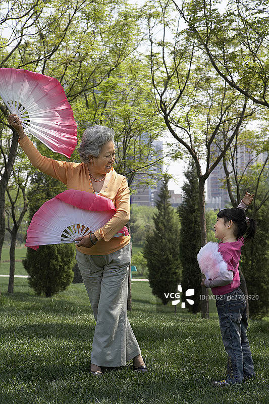 老人和女孩在公园练习扇舞图片素材