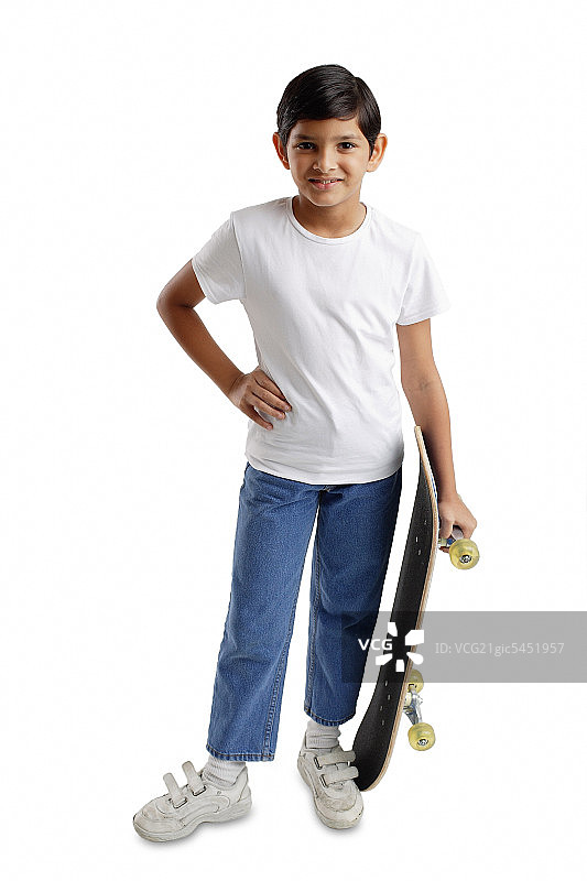 男孩站着，拿着滑板，手放在臀部图片素材