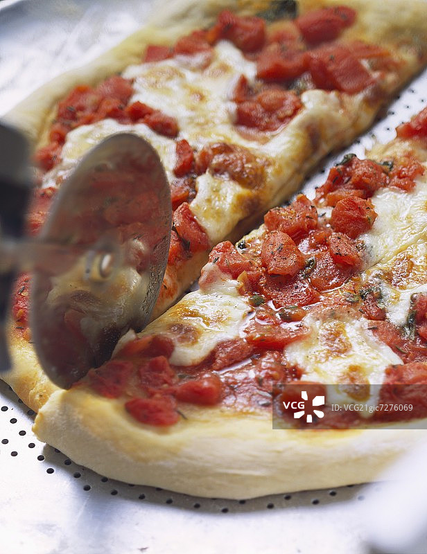 用披萨刀切蕃茄和马苏里拉披萨图片素材