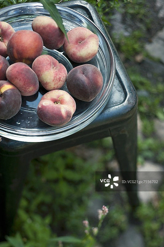 花园桌子上的玻璃碗里装着新鲜的桃子图片素材