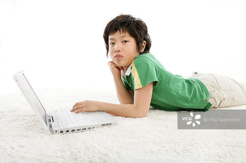 男孩(12-13岁)躺在地毯上，手提电脑，肖像图片素材