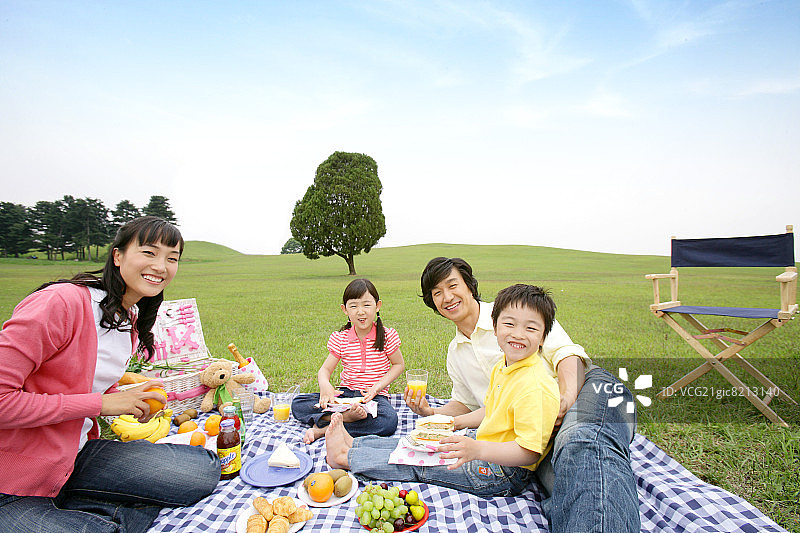 父母和孩子(6-7岁)坐在野餐毯上，画像，微笑图片素材