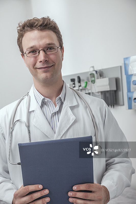 微笑的医生拿着一个剪贴板的肖像图片素材