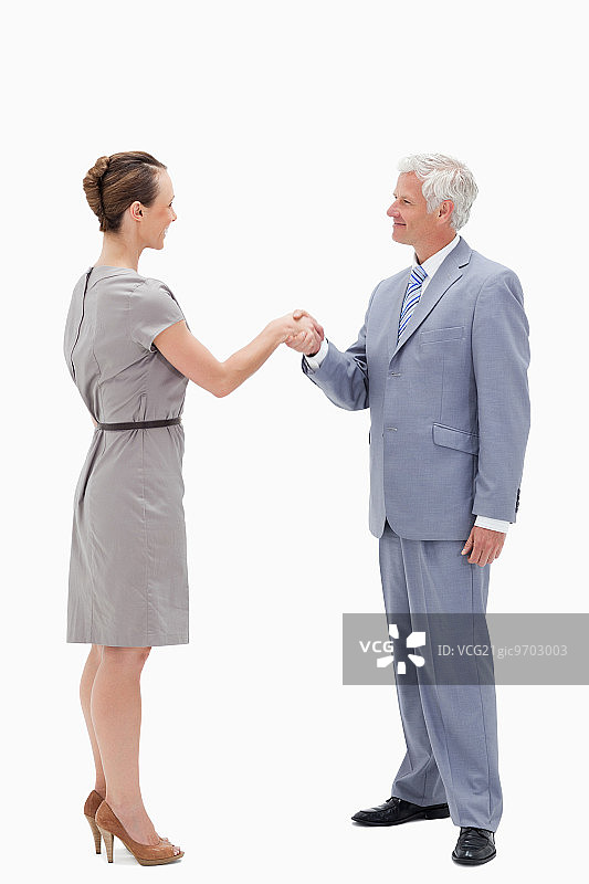 白发商人面带微笑，在白色背景下与一名女子握手图片素材