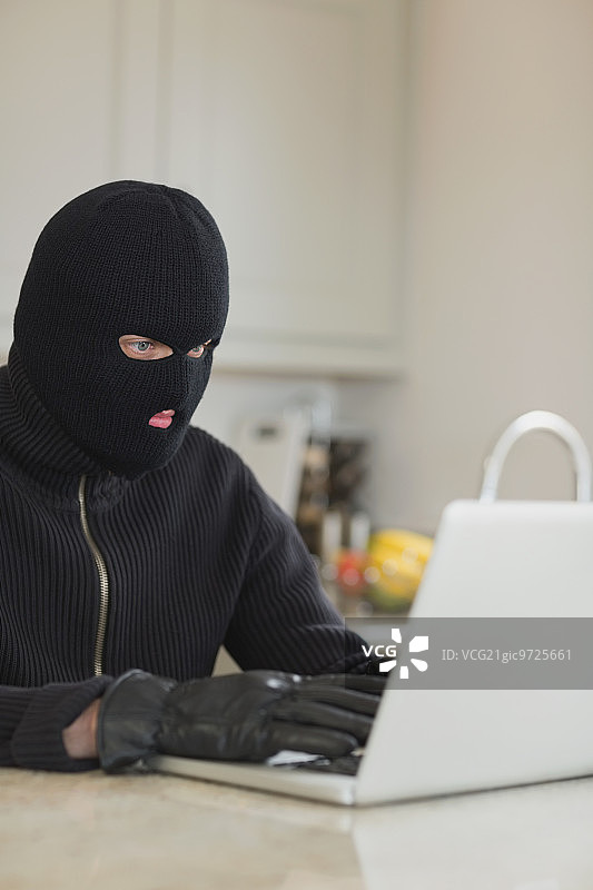 坐在厨房里入侵笔记本电脑的强盗图片素材