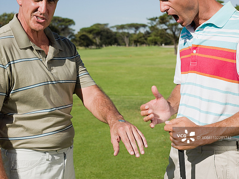 两个成熟的男人一起打高尔夫球，抛硬币图片素材