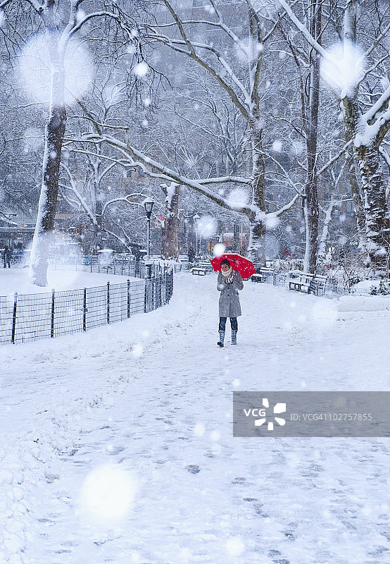 在一个下雪天拿着红伞走的女人图片素材