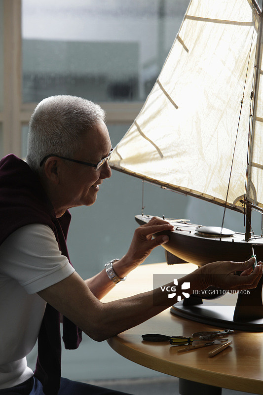 在模型帆船上工作的老年人的概况图片素材