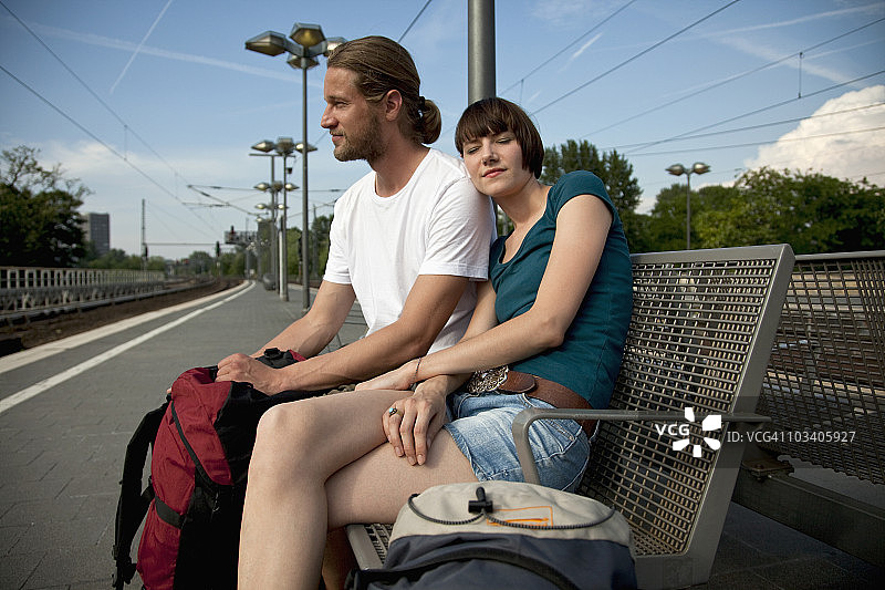一对无聊的背包客夫妇在站台上等待他们的火车图片素材
