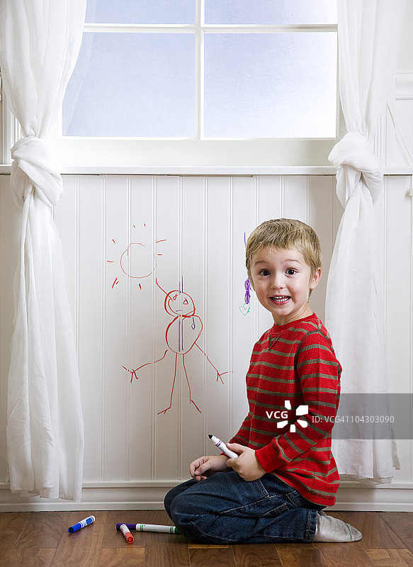 小男孩在墙上画画图片素材