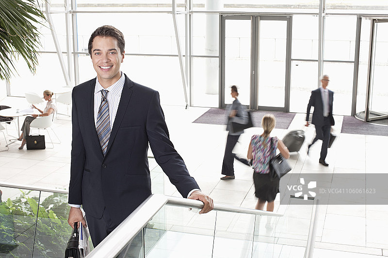 一个快乐的商人的肖像，背景是机场里的人图片素材