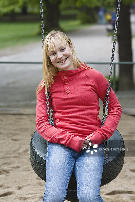 微笑少女坐在轮胎秋千上的肖像图片素材