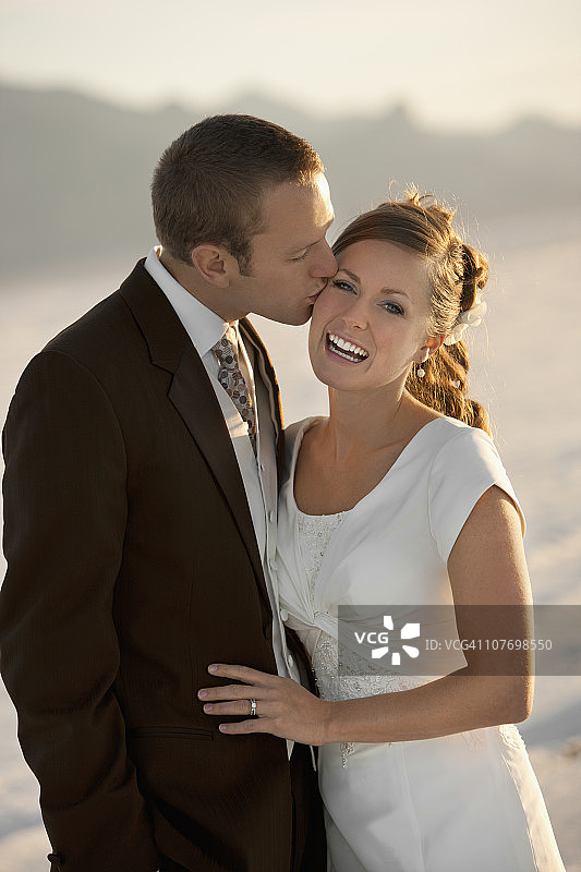 美国，犹他州，波恩维尔盐滩，新郎亲吻新娘在沙漠图片素材