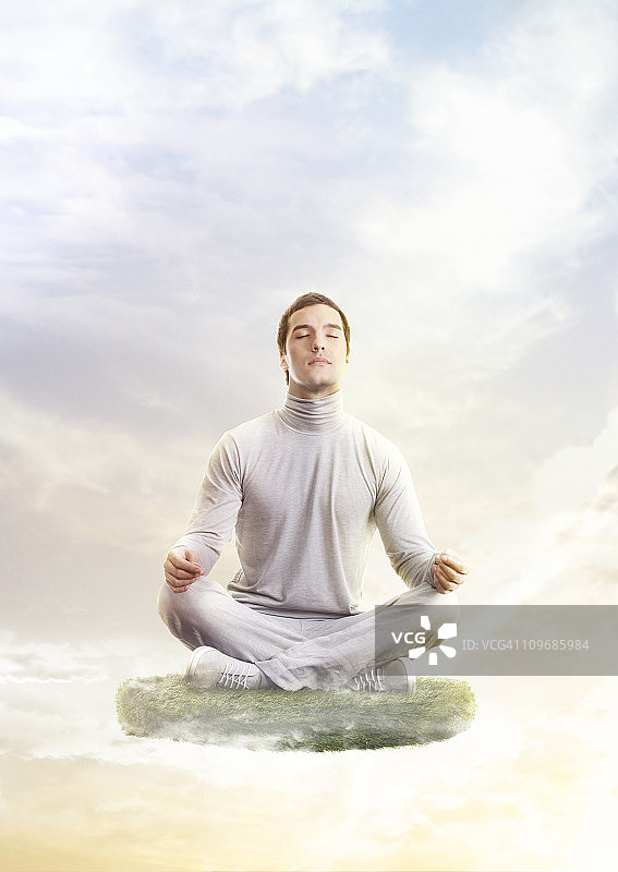 一个瑜伽姿势的男人，漂浮在一片草地上图片素材