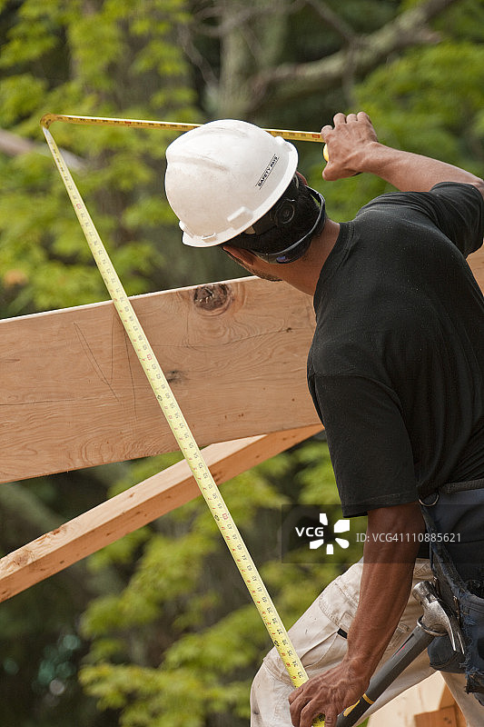 西班牙木匠用卷尺测量正在建造的房子的椽子图片素材