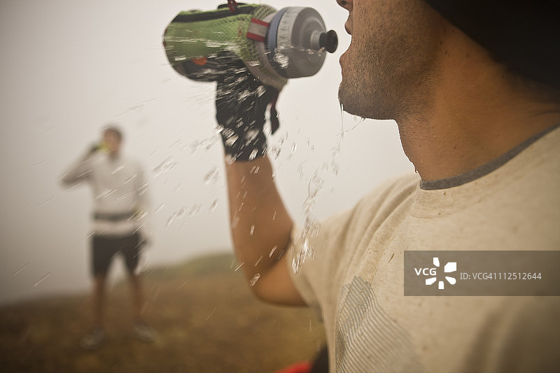 一名男子在跑步时喝着水瓶里的水。图片素材