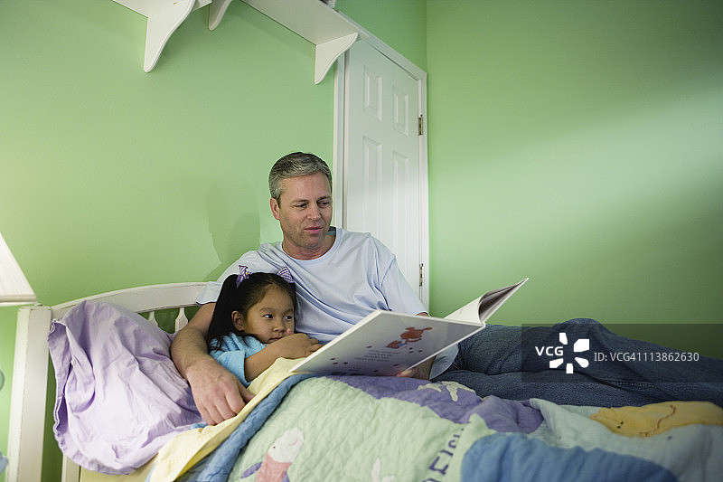 父亲和女儿在卧室看书图片素材