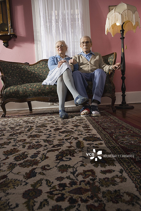 一对深情的老夫妇坐在客厅的沙发上图片素材
