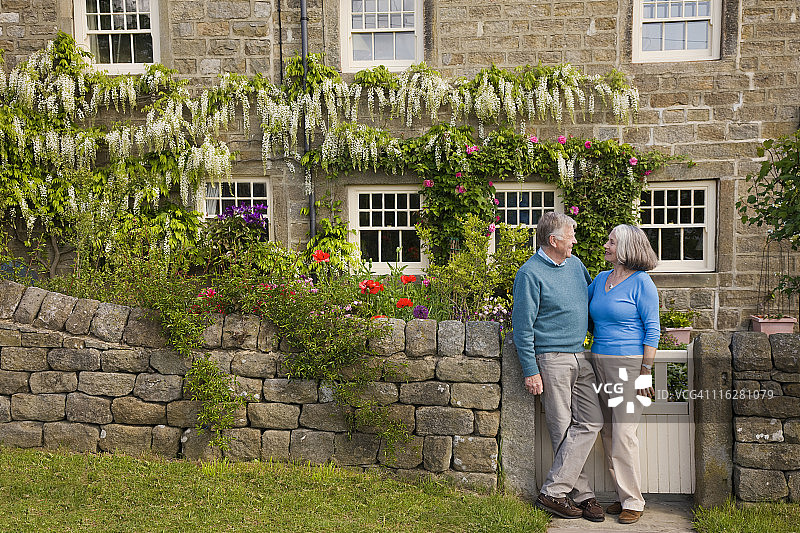 一对退休夫妇站在一所乡村小屋前图片素材