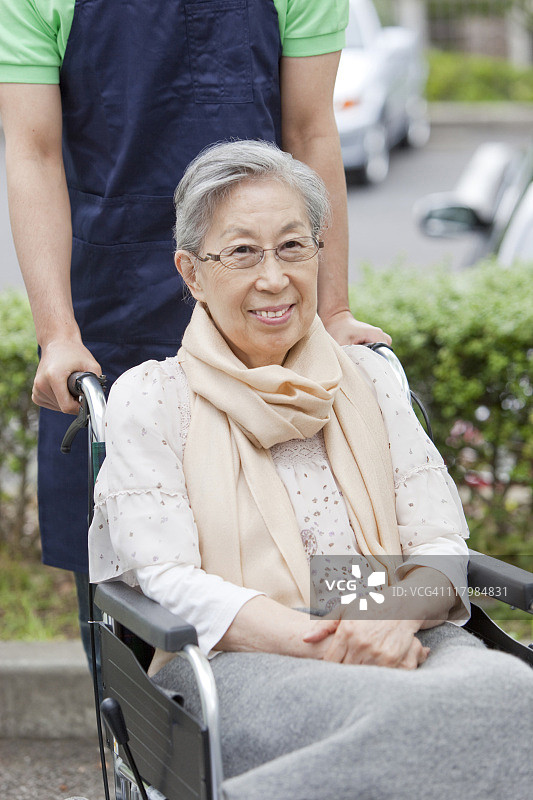 日本本州神奈川县，医疗工作者推着轮椅上的老年妇女图片素材