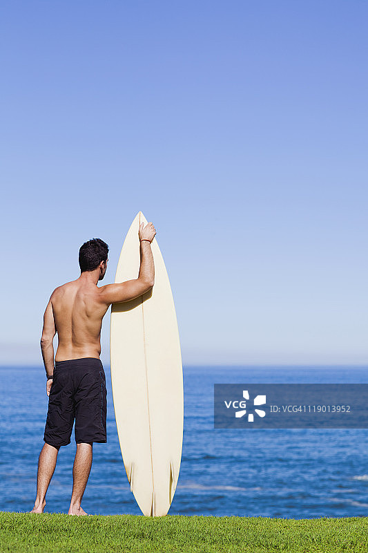 男子在海边抱着冲浪板图片素材