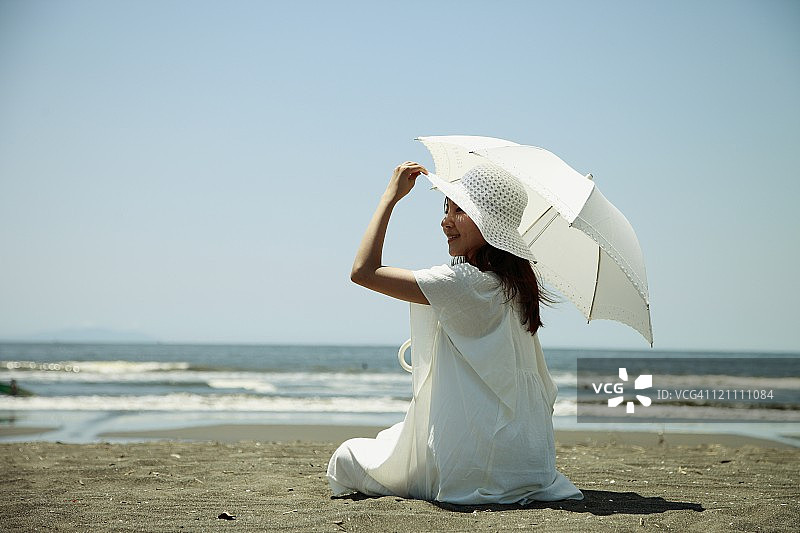 沙滩上拿着阳伞的年轻女子图片素材