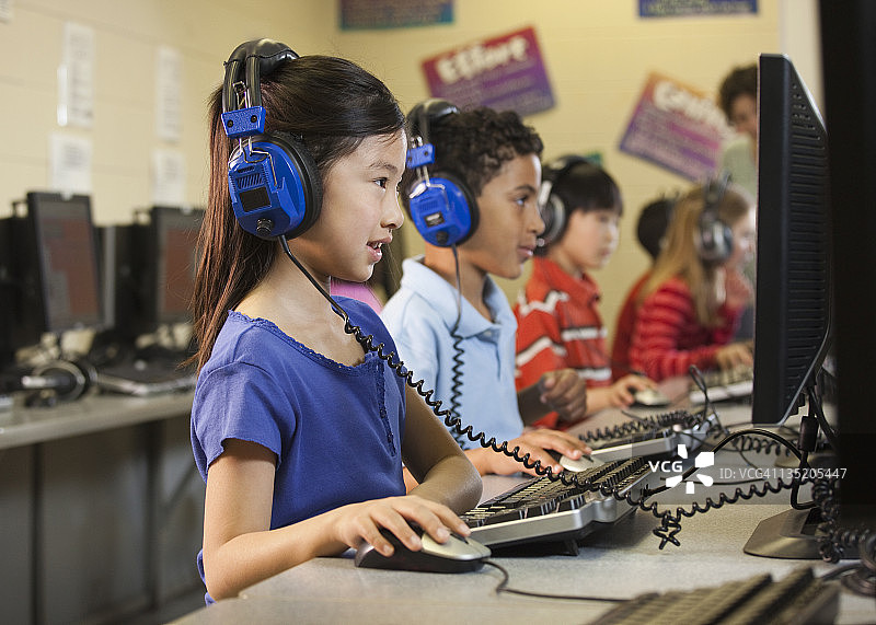 学生们在教室里用电脑听耳机图片素材