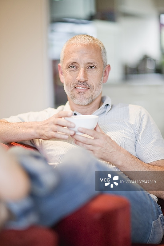 男人坐在扶手椅上喝咖啡图片素材