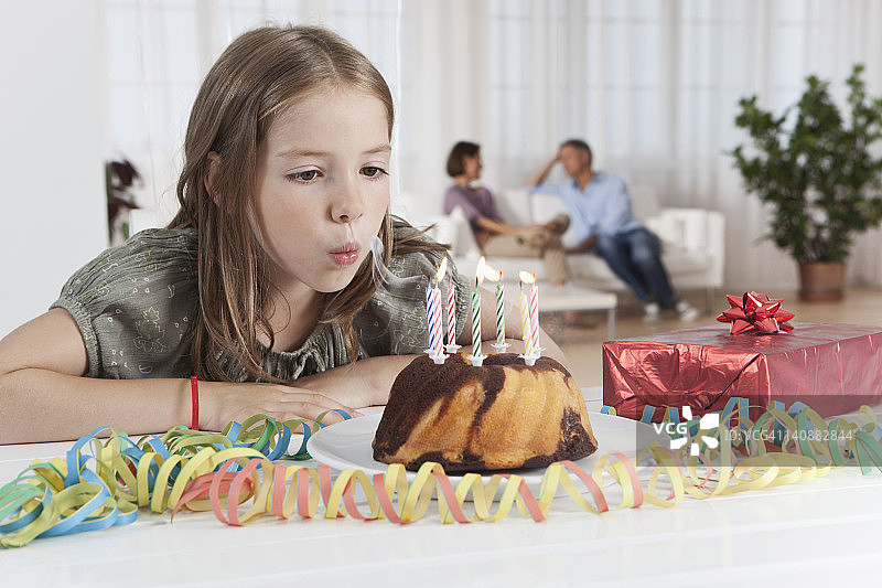 德国，慕尼黑，女孩吹蜡烛的生日蛋糕，父母在背景图片素材