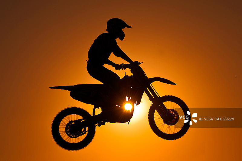 日落时摩托车越野赛的剪影图片素材