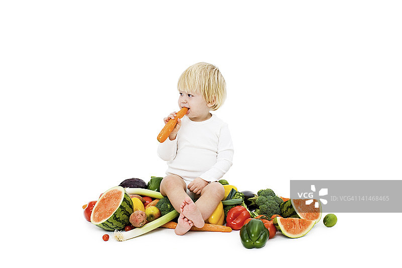 摄影棚拍摄的被新鲜蔬菜包围的男婴图片素材