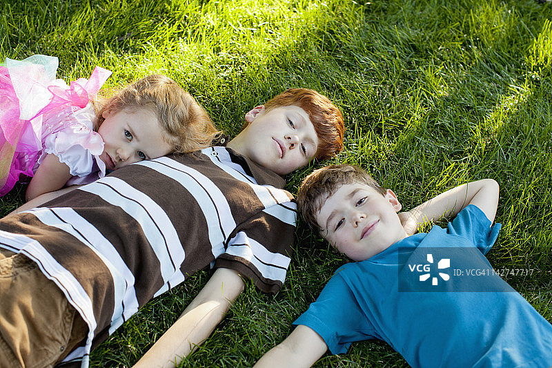 孩子们(4- 5,6 - 7,12 -13)躺在草地上图片素材