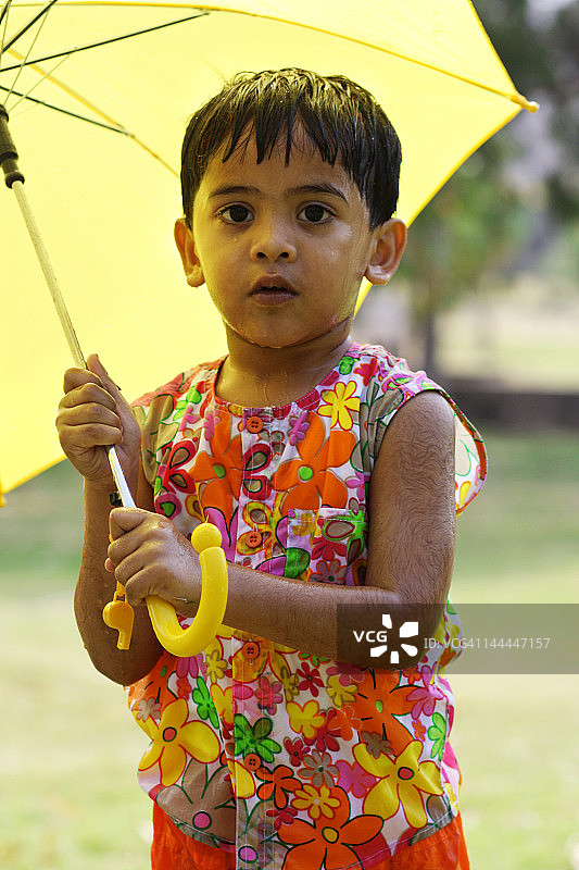一个小孩拿着一把黄色的伞图片素材