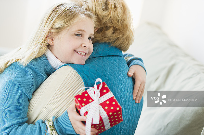 美国，新泽西州，泽西城，孙女(8-9岁)拥抱祖母和抱着礼物图片素材