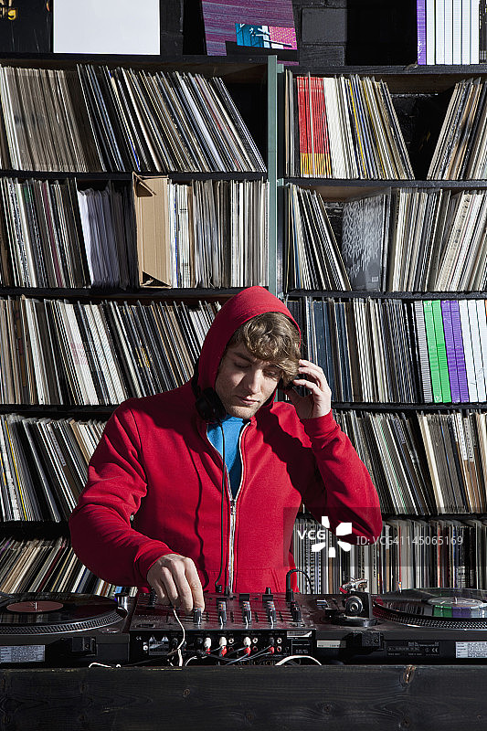 一个年轻人在一家唱片店使用音响和混音器图片素材